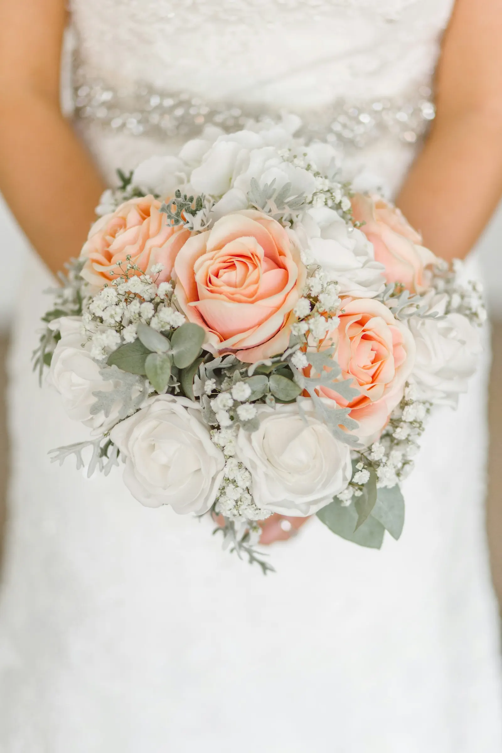 Bride holding a bouquet of peach roses