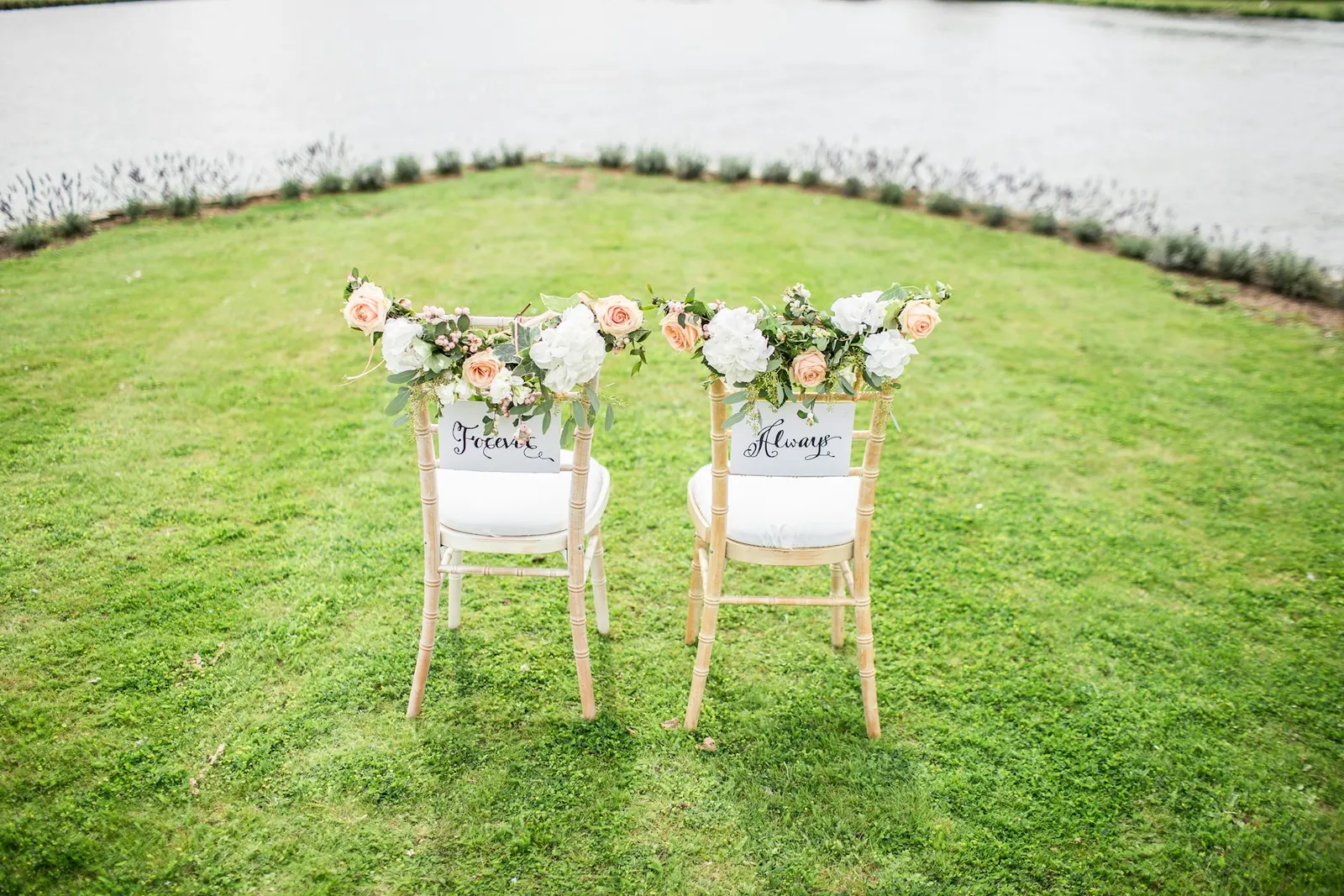 Bride and groom chairs decorated with flowers on a green lawn