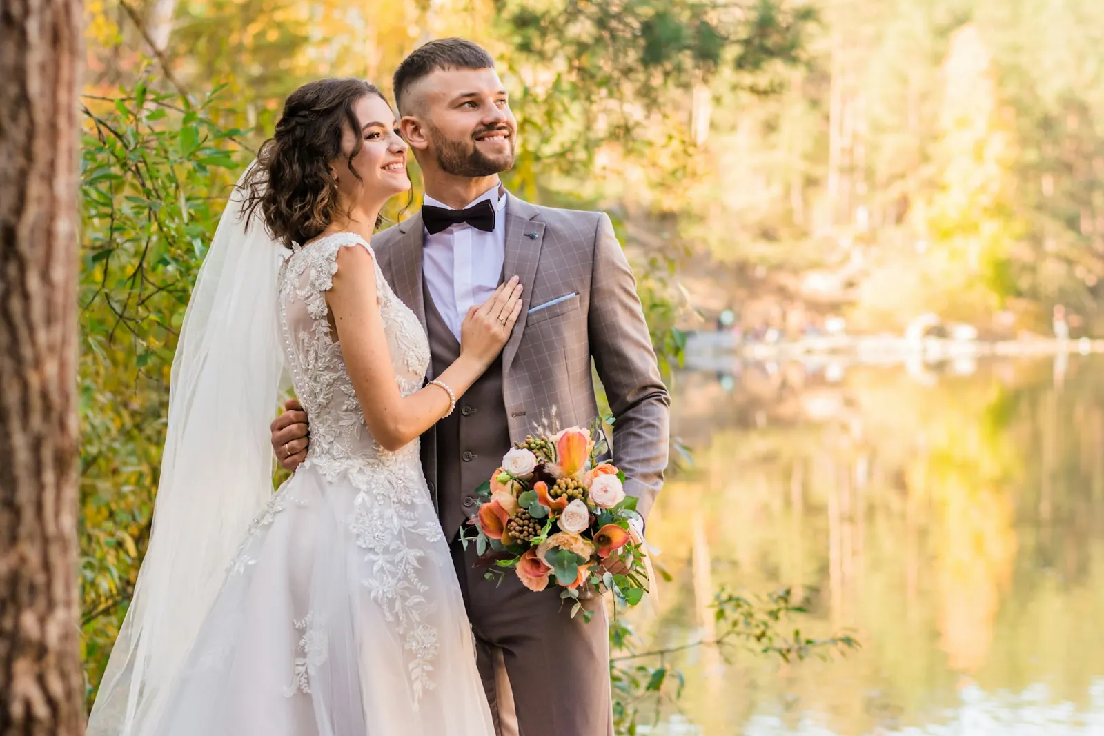 Bride and groom by a mountain lake at golden hour